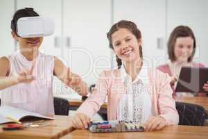 School girl sitting in classroom using virtual reality headset