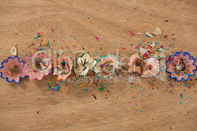 Colored pencil shavings on wooden background