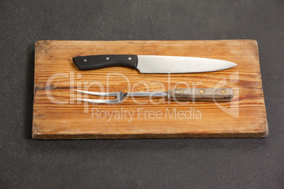 Knife and fork on wooden board