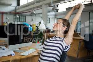 Female graphic designer sitting on chair and stretching her arms