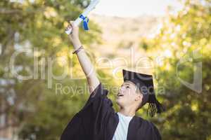 Excited graduate schoolboy with degree scroll in campus