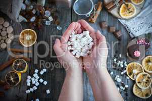 Two female hands holding a bunch of white marshmallow on the tab