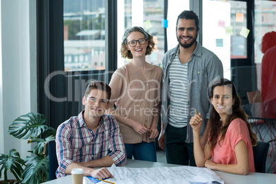 Portrait of smiling business executives with blueprint on table Portrait of smiling business executives with blueprint on table