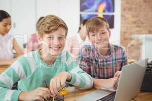 Smiling schoolboys working on electronical project in classroom