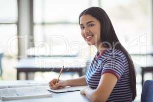 Portrait of happy schoolgirl studying in classroom
