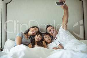 Parents and kids taking a selfie on bed