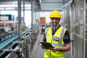 Portrait of smiling factory worker using a digital tablet