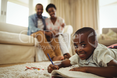 Portrait of boy writing in a book while lying on a rug