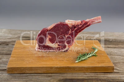 Rib chop steak and rosemary herb on wooden board against wooden background