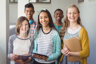 Portrait of smiling students standing with digital tablet and notebook in corridor Portrait of smiling students standing with digital tablet and notebook in corridor