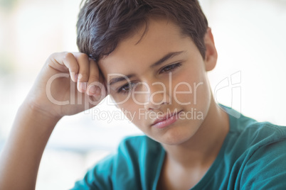 Thoughtful schoolboy sitting in classroom