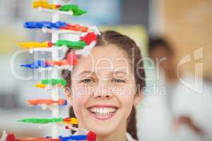 Portrait of happy schoolgirl experimenting molecule model in laboratory