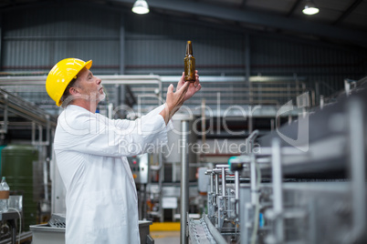 Factory worker examining a bottle in factory