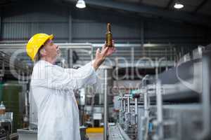 Factory worker examining a bottle in factory