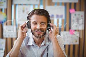 Close-up of male graphic designer listening music on headphone