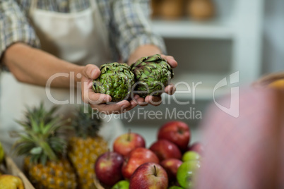 Vendor offering custard apples to the woman at the counter