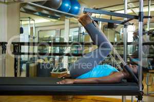 Determined woman performing stretching exercise on reformer