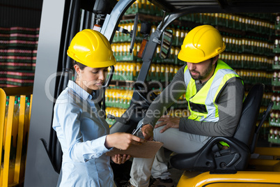 Factory workers checking record on clipboard in factory