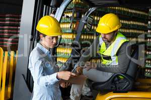 Factory workers checking record on clipboard in factory