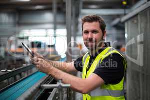 Portrait of smiling factory worker using a digital tablet