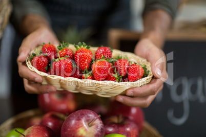 Vendor holding a basket of strawberries at the grocery store