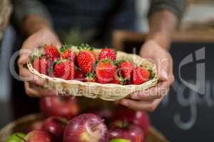 Vendor holding a basket of strawberries at the grocery store