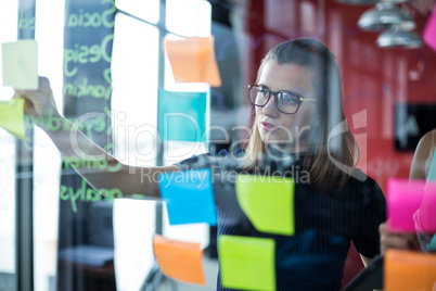 Business executive sticking sticky notes on glass