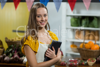 Woman vendor holding digital tablet at the counter at grocery store