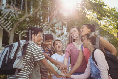 Happy school kids forming hand stack in campus