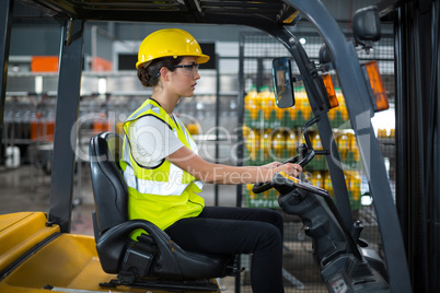 Female factory worker driving forklift