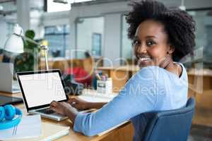 Female graphic designer using laptop in creative office