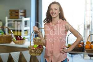 Smiling woman holding a basket of apples in the grocery store