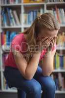 Sad schoolgirl sitting in library