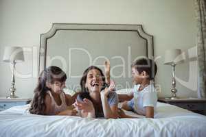 Mother and kids lying on bed in bedroom