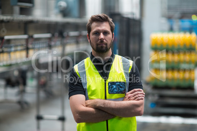 Factory worker standing with arms crossed in factory