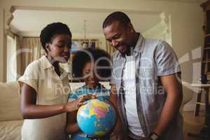 Parents and daughter looking at globe in living room