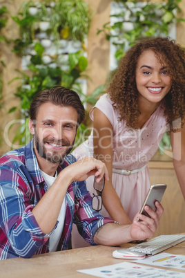 Portrait of executives at desk using mobile phone