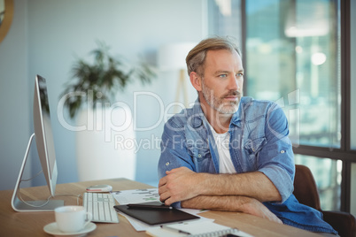 Thoughtful graphic designer sitting at desk