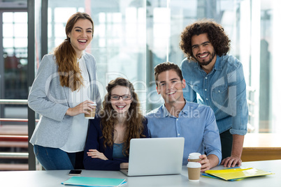 Portrait of smiling business team working on laptop in meeting