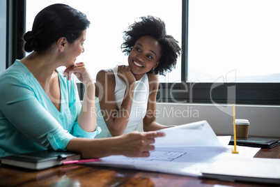 Female graphic designers discussing over the document