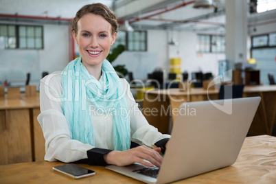 Female graphic designer using laptop at desk