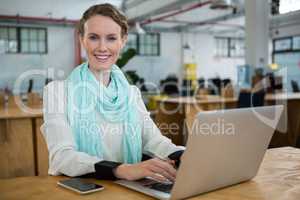 Female graphic designer using laptop at desk