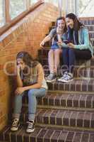 School friends bullying a sad girl in school corridor