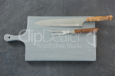 Knife and fork on wooden board