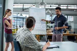 Business executives discussing over flip chart during meeting