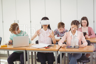 School girl sitting in classroom using virtual reality headset