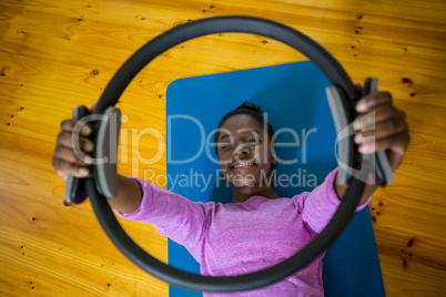 Smiling fit woman exercising with pilates ring on mat
