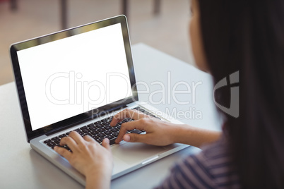 Schoolgirl using laptop in classroom