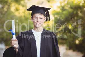 Portrait of graduate schoolboy standing with degree scroll in campus
