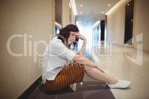Portrait of sad female business executive sitting in corridor